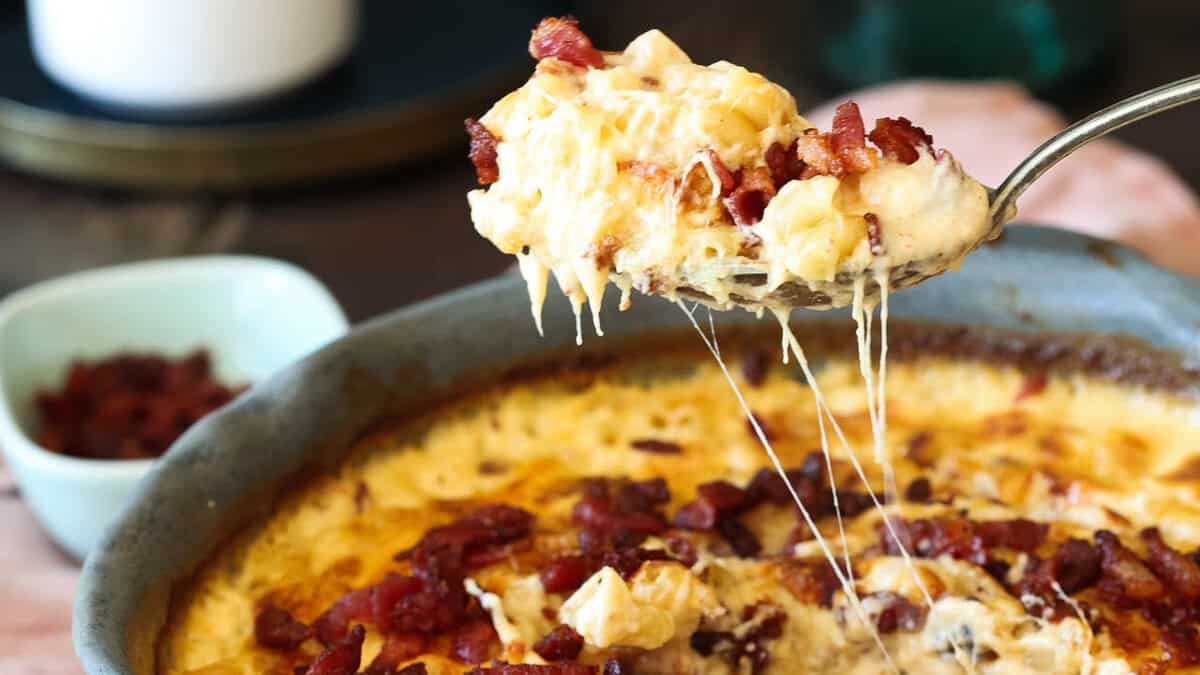 A spoonful of bacon mac and cheese being lifted out of the pan.