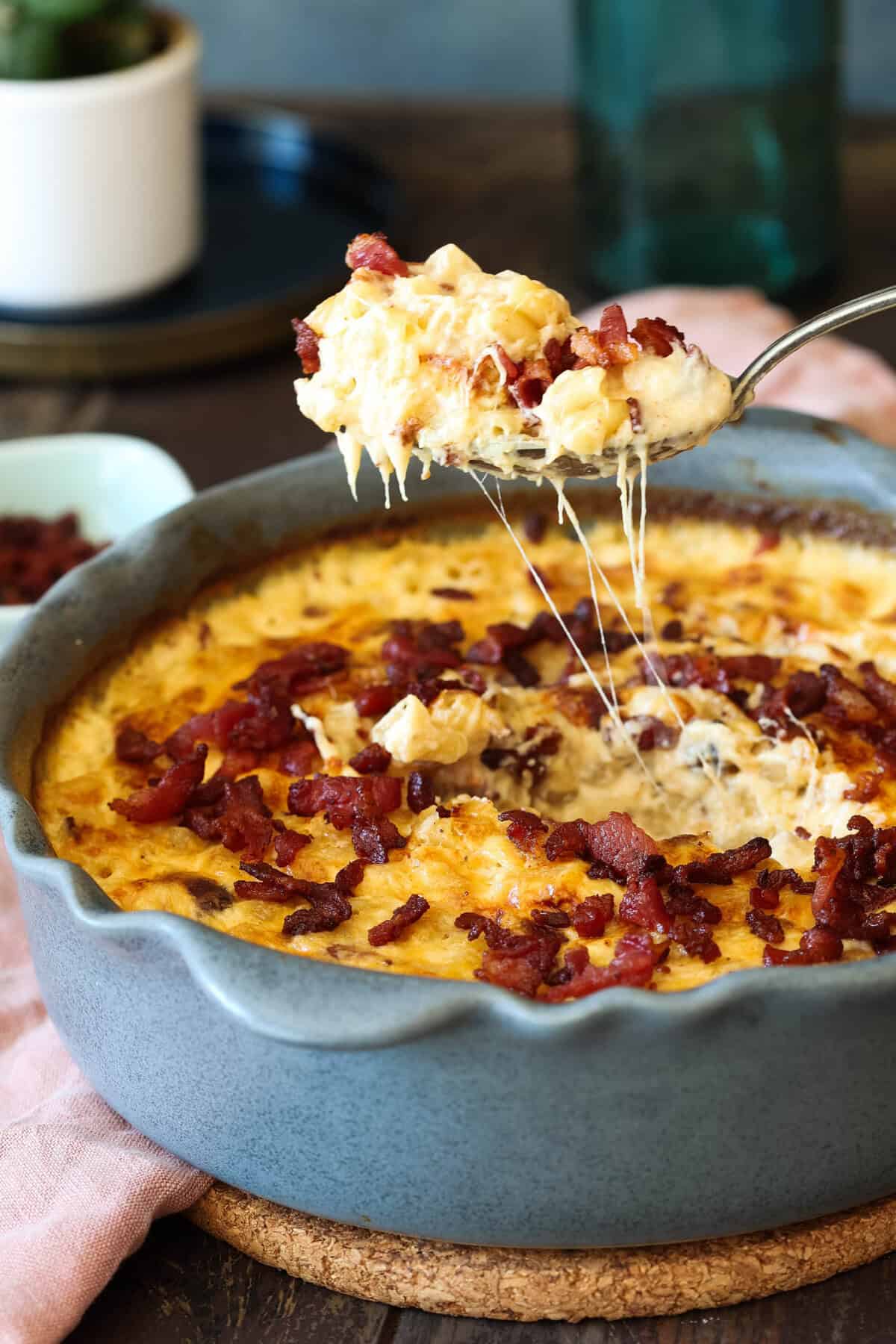 A spoonful of bacon mac and cheese being lifted out of the pan.