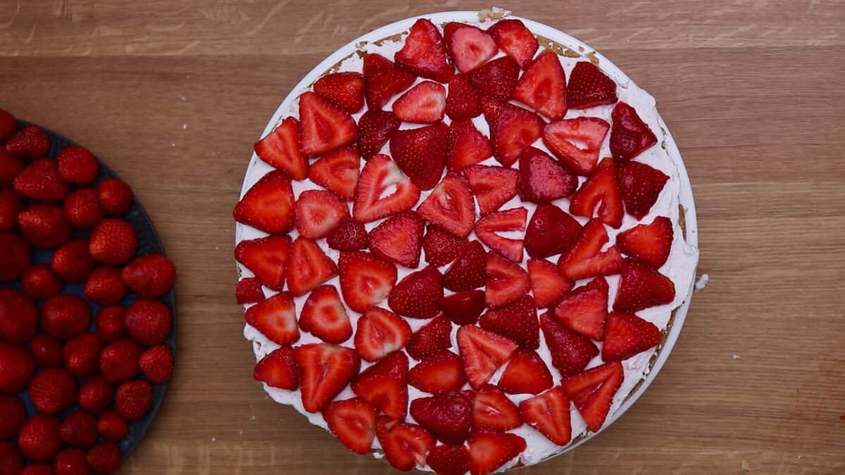 A strawberry cream cake after finishing the first layer with cake base, strawberry whipped cream and sliced strawberries.