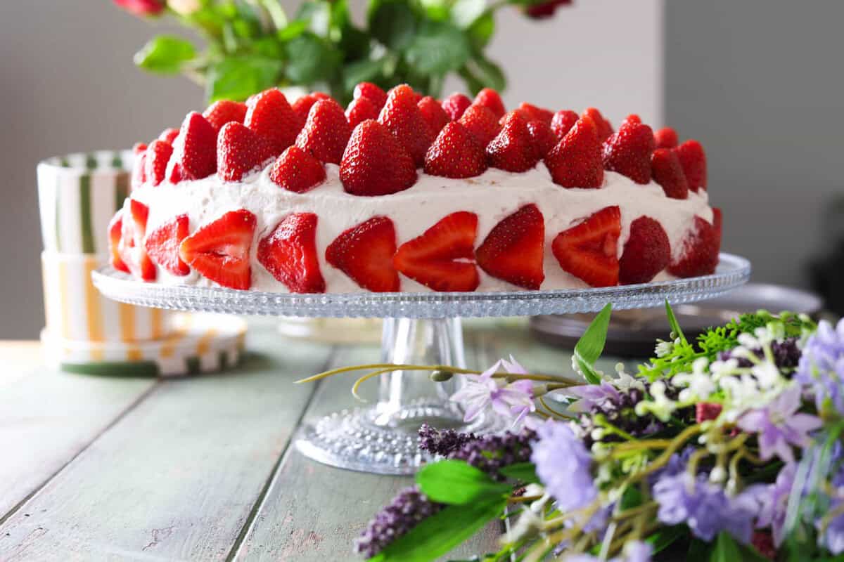 A strawberry cream cake topped with lots of whole strawberries.