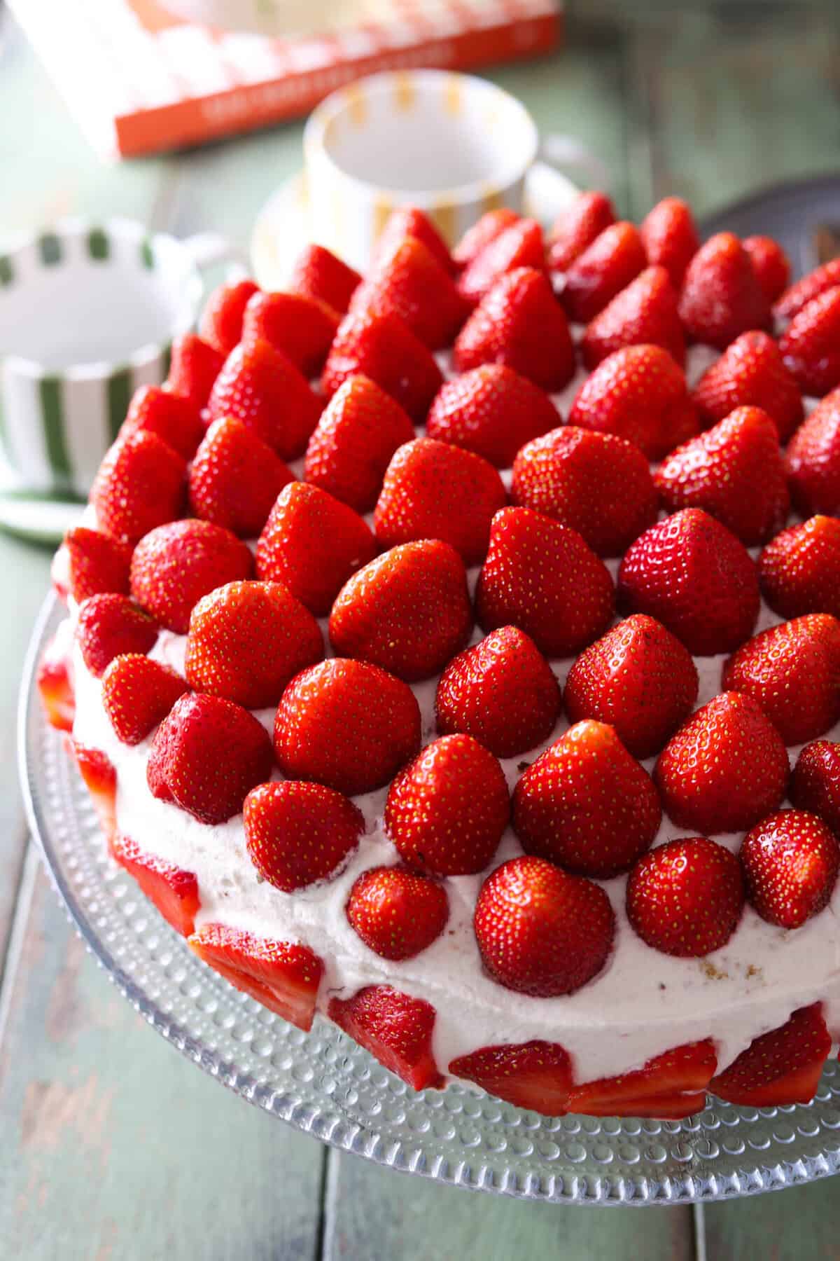 A strawberry cream cake topped with lots of whole strawberries.