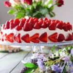A strawberry cream cake topped with lots of whole strawberries.