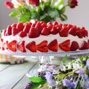 A strawberry cream cake topped with lots of whole strawberries.