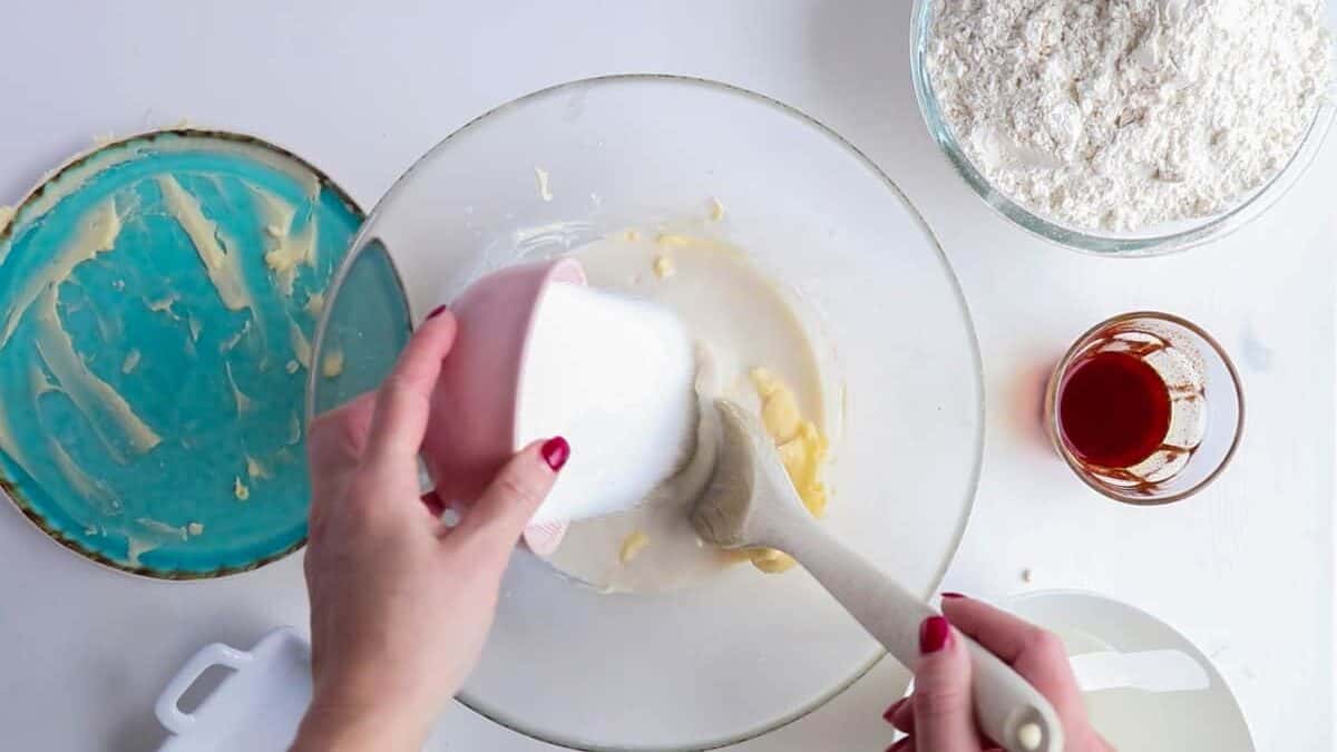 Adding sugar to a mixture of milk, butter and yeast to make lussekatter.